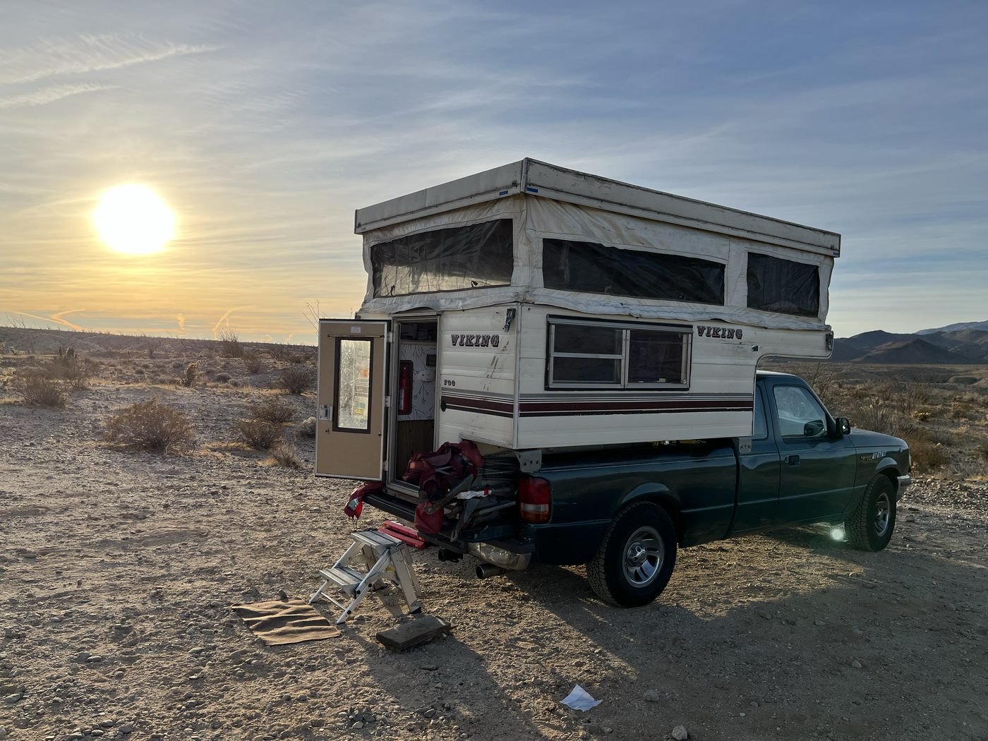 Truck camper set up in the desert at sunset