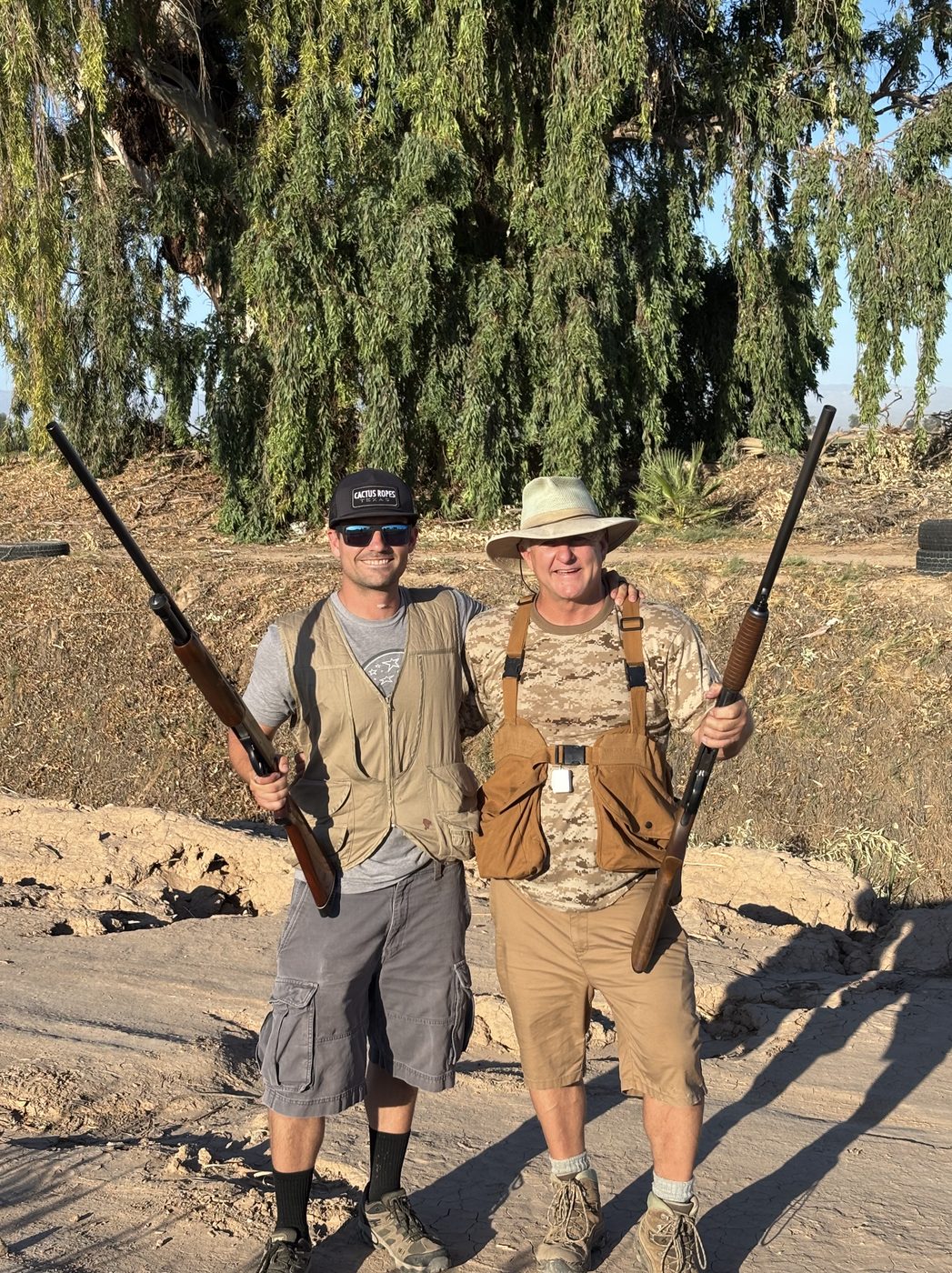 Trent and his father outdoors, each holding a shotgun