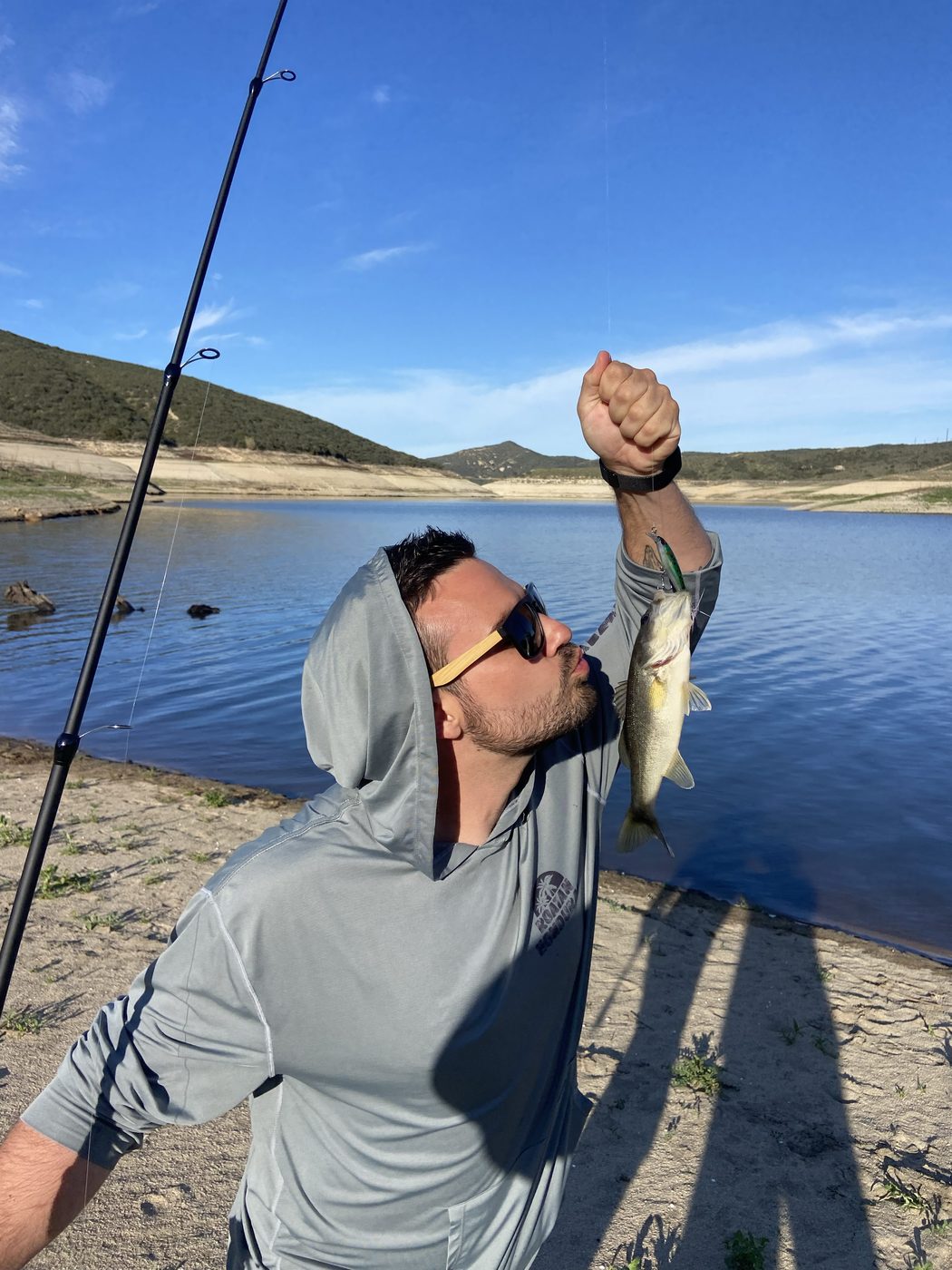 Trent holding up a bass he caught at a lake